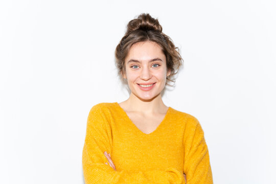 Smiling woman in yellow sweater posing indoors with a plain background