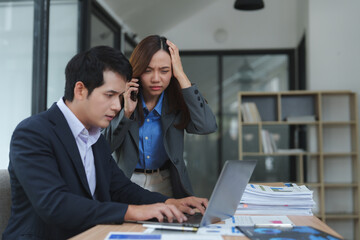 Stressed businesspeople having problems at work while using laptop and phone