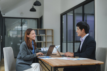 Asian businesspeople working together using laptop in office meeting discussing project