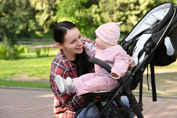 Mother with her cute baby in stroller at park