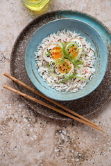 Turquoise plate with mixed rice and soy-marinated eggs on a beige granite background, vertical shot with space, top view