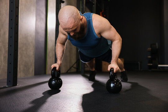 Sportsman doing kettlebell push up during workout in gym