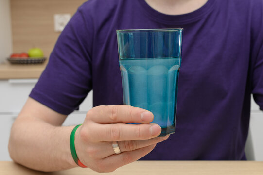 Mężczyzna trzyma w dloni szklankę z rozpuszczonym suplementem diety, kreatyna