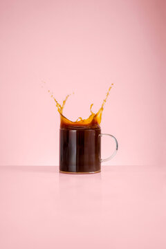 Abstract caffeine concept, glass mug with black coffee and splashes