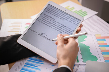Electronic signature. Man using stylus and tablet at table, closeup