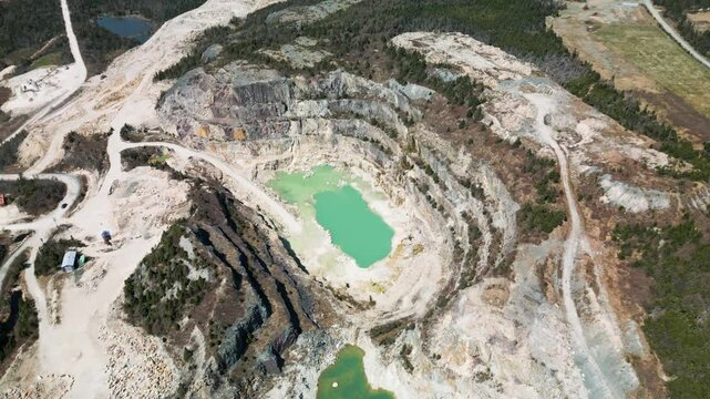 Drone shot of an open talc mine quarry in Manuels, Newfoundland Canada revealing the toxic aquamarine blue water within
