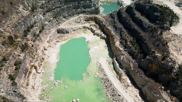 Drone shot of an open talc mine quarry in Manuels, Newfoundland Canada revealing the toxic aquamarine blue water within