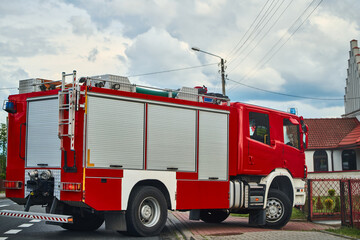 Red fire engine driving in suburban neighborhood.