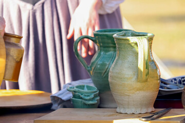 Assortment of rustic handmade bowls, cups, and jugs in a wicker basket on display at traditional outdoor market stall