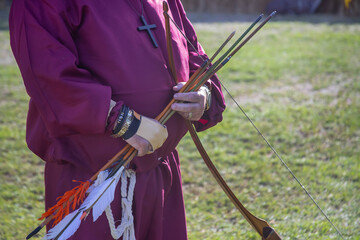 Archer in historical costume aims longbow at a target during a Medieval Fair during a local...
