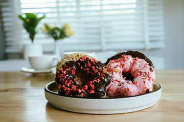 Assorted colorful donuts with icing and sprinkles are arranged on a white background, showcasing a sweet, delicious, and sugary treat.