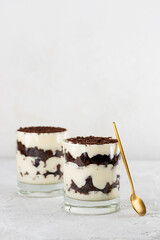 Black forest trifle with cherry, cream with shea butter and chocolate biscuit in a glasses with golden spoon . Vegan dessert. Vertical orientation.