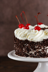 Half of the Black forest cake, Schwarzwald pie, dark chocolate and cherry on a brown background. Vegan food, sugar, lactose and gluten free. Vertical orientation.