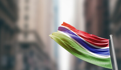 The Gambia national flag waving on street. A beautiful with mast with blur buildings. The Gambia national flag for independence day.