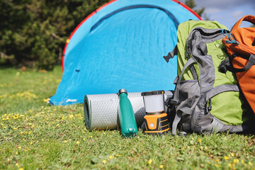 Eco-friendly camping gear with backpack and reusable bottle in front of tent