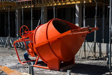 Construction site with an orange concrete mixer in use