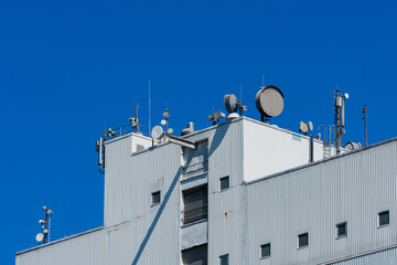 Communication antennas on building against clear blue sky