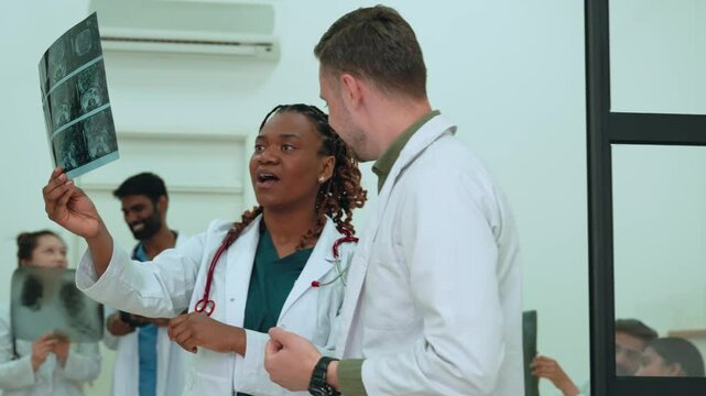 Medical team members comparing medical scans, discussing patient details while working together in contemporary clinical setting, showcasing professional teamwork