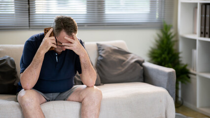 An elderly man is talking on the phone with a distressed look.