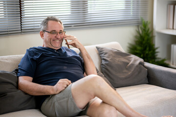 An elderly man is talking on the phone with a happy expression.