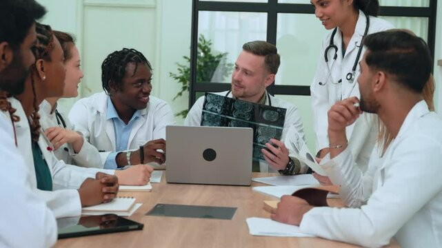 Medical team collaborating, reviewing brain scans and x-rays on laptop, sharing insights during professional healthcare strategy meeting, highlighting interdisciplinary communication
