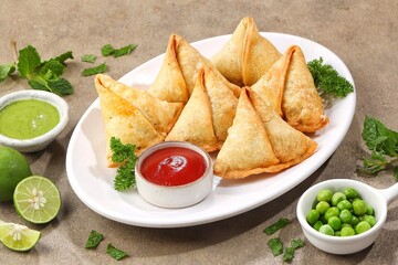 Samosa or samboosa is a triangular fried pastry filled with boiled potatoes seasoned with spices mixed with peas, onions, coriander leaves, and sometimes paneer.