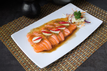 Salmon sashimi with ponzu sauce and grated daikon on white plate