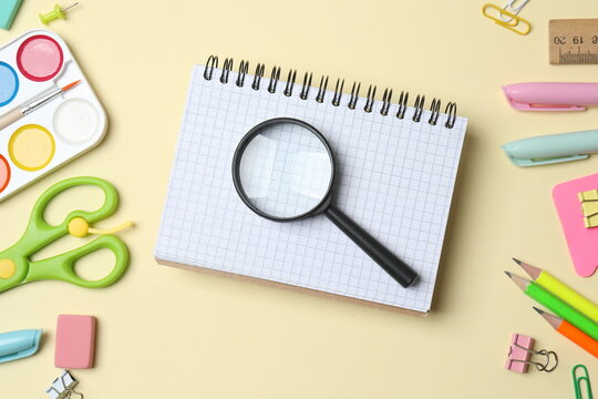 Various colorful school supplies including notebook, magnifying glass and a paints placed neatly on a color background, top view - Powered by Adobe