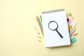 Various colorful school supplies including notebook, magnifying glass and a paints on a color...