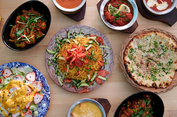 A table with many different types of food, including a salad, a plate of rice, and a bowl of soup