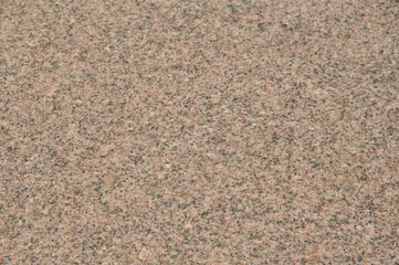 A close up of a stone surface with a lot of small rocks. The surface is brown and has a lot of texture