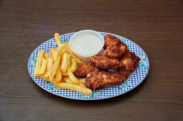 A plate of chicken wings and french fries. The chicken wings are covered in sauce and the fries are golden brown