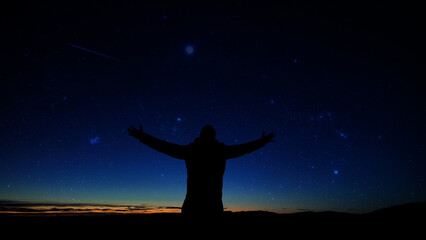 Silhouette of a man and countryside under the stars and planets.