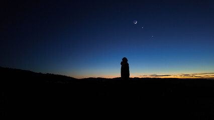Silhouette of a man observing Milky Way stars, planets and other celestial objects from a dark...