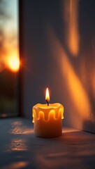 Burning candle casting shadows on a wall with warm light