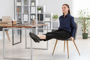 Beautiful woman exercising with chair in office