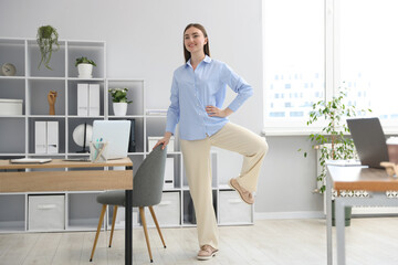 Beautiful woman exercising with chair in office