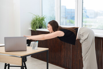 Beautiful woman exercising with chair in office