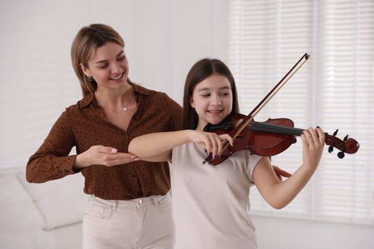 Woman teaching teenage girl to play violin at music lesson