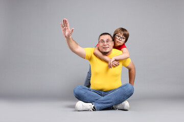 Father and his son on grey background, space for text