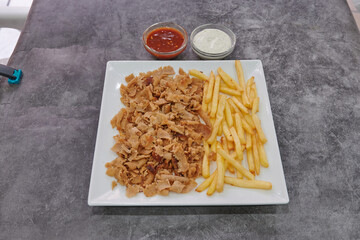A plate of meat and french fries. The meat is cut into small pieces and the fries are golden brown