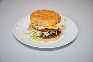 A hamburger with a fried egg on top. The egg is on the bun and the burger patty is on the bun