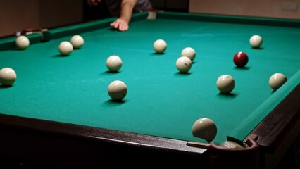 Playing Russian billiards on a green table. Billiard player hits the white ball. Good goal. Successful attempt. A great game. Hobby pastime. Corner pocket side view close-up. Professional shot
