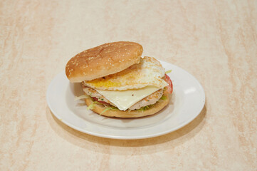 A sandwich with a piece of cheese and a piece of ham on it. The sandwich is on a white plate