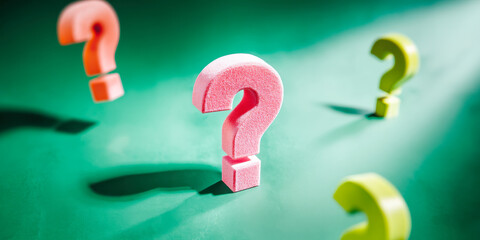 Colorful question marks on green background create a playful and vibrant atmosphere for inquiries