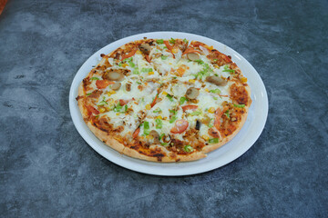 A pizza with vegetables on it is sitting on a white plate. The pizza is cut into eight slices