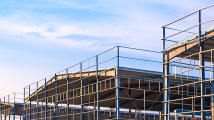 Metal structure of 3 warehouse industry factory buildings in construction site against blue sky background, low angle and perspective side view	