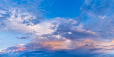 Colorful dramatic clouds during sunset, with layers of light and shadow across the sky. A panoramic view capturing the beauty of changing weather and natural light.
