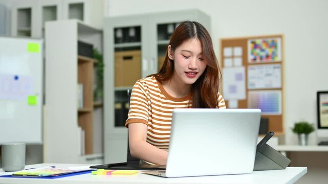 Young female designer using pen tablet and color palette while working in a modern creative office and color theory themes.