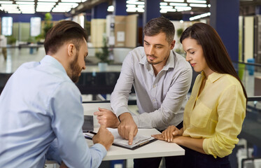 Sale manager consulting, explain couple customers in show room, marketing, showing clients modern samples, family making purchase, choosing items for home repair, bath room, seller helping, guiding